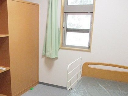 小さな窓がついている施設内の居室の様子。右側にベッドがあり左側に収納がついている様子