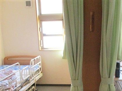 左側にベッド、右側に小さな窓とカーテンが見えている写真