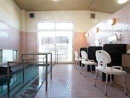 シャワーチェアが設置されたシャワースペースがあり、大きな浴槽には手すりが付き、窓も設置されている。