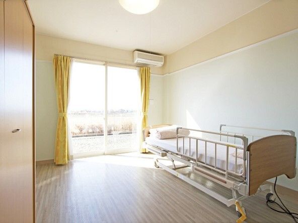 エアコンが付いたフローリングの部屋には寝具付きのベッドが置かれ、大きな窓もあり、収納スペースが付いている。