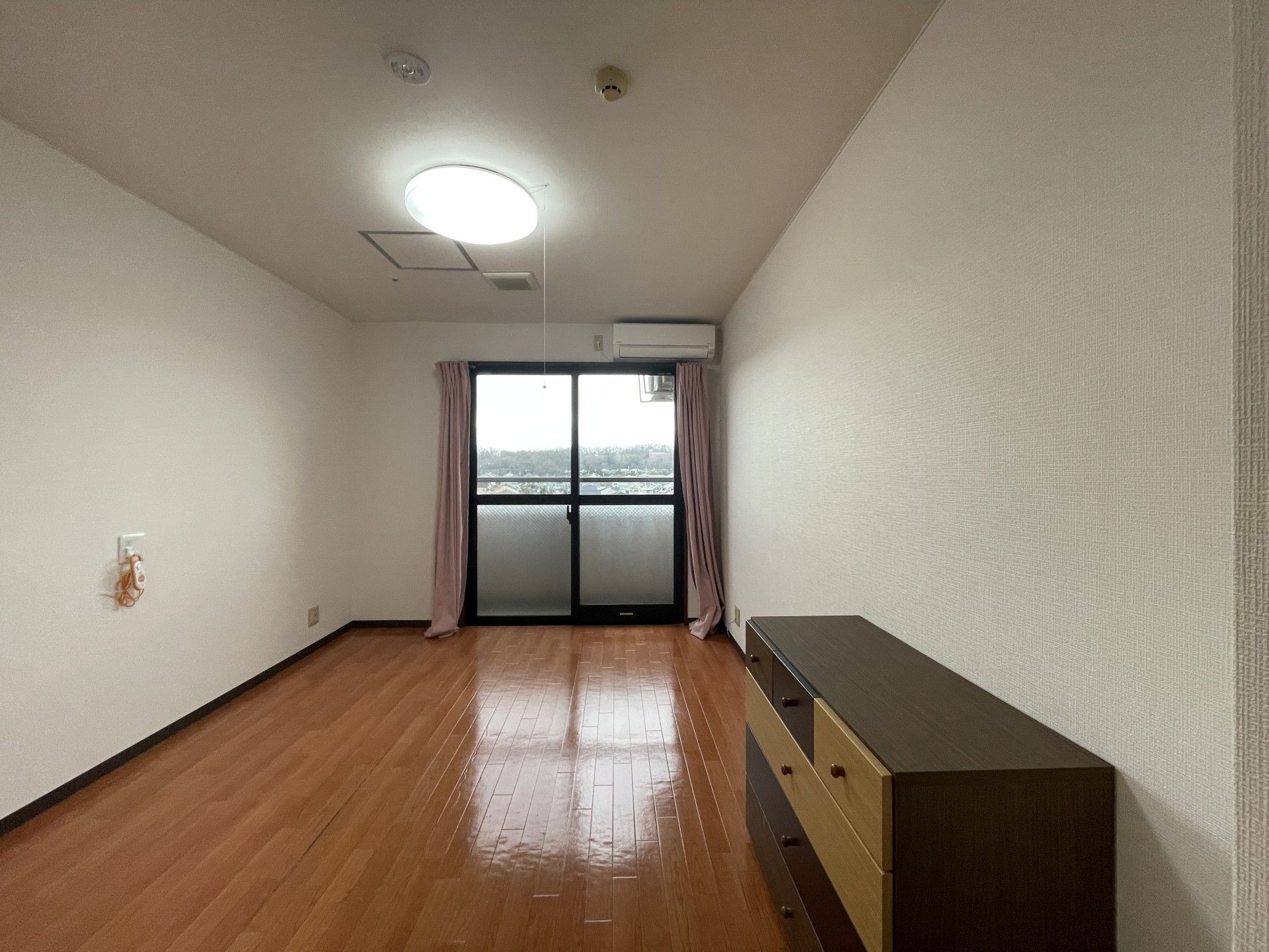 ベッドが二つ並び、それぞれに寝具がセットされている。ベッドサイドにはオレンジの緊急通報装置もあり、向かい側の壁際にはソファもある。