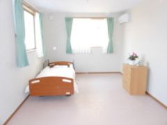 居室のベッドには収納家具が付き、窓にはカーテンが付けられている。