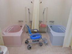 個浴が二つ置かれた広い浴室。浴室用車いすやシャワー、手すりなどもある。