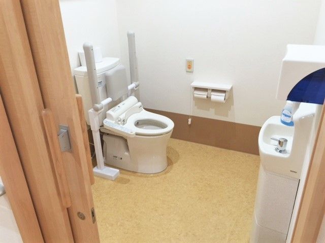 広いトイレには呼び出しボタンが付き、便座には手すりと背もたれもある。手洗い場にはソープが置かれている。
