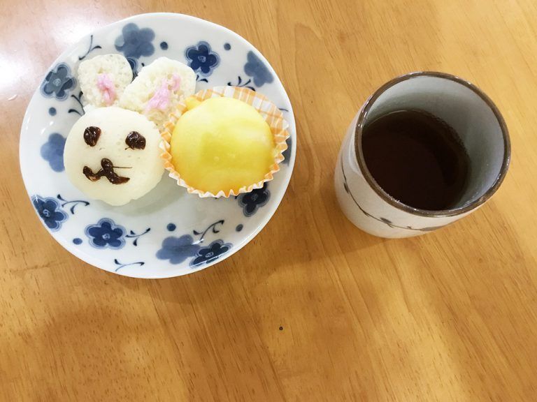 月を見立てた黄色いまんじゅうと、白い蒸しパンにチョコレートでウサギの顔を描いたおやつ