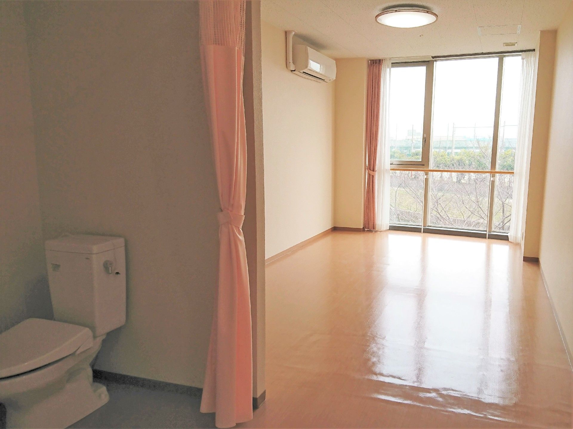 ドアレスのトイレが付いている個室の様子。奥のほうにベッドが置いてあるのが分かる