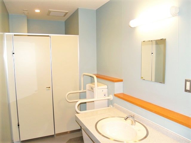 施設内にある手すり付き便器とその周りにある水回り設備の写真