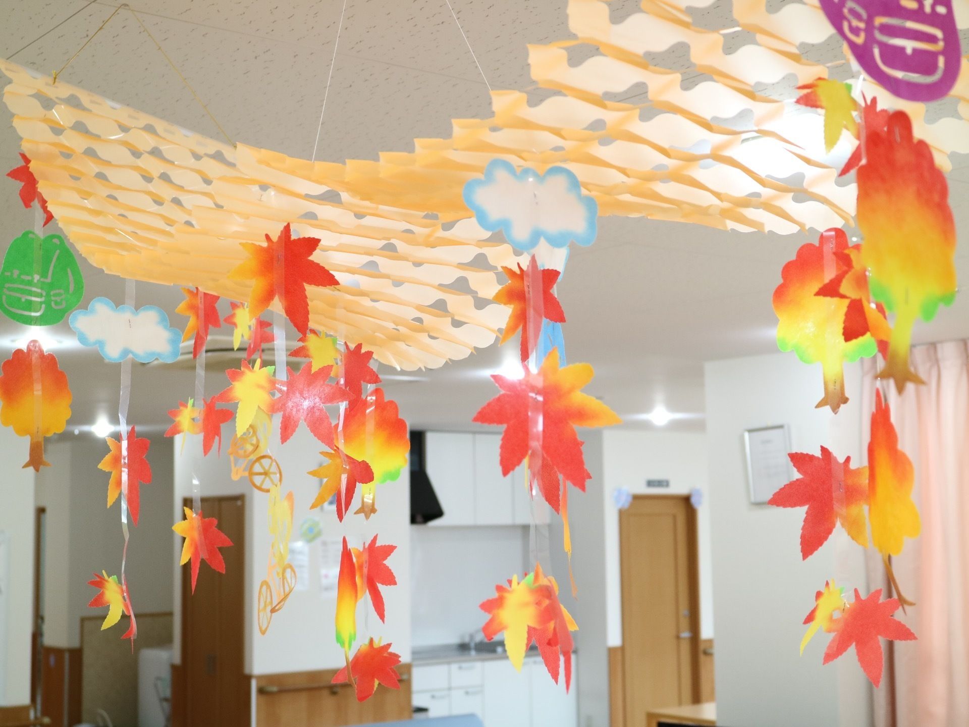 紅葉した木々や葉、リュックサックなどが型取られた切り紙。糸やテープなどを活用して天井から吊り下げられている。