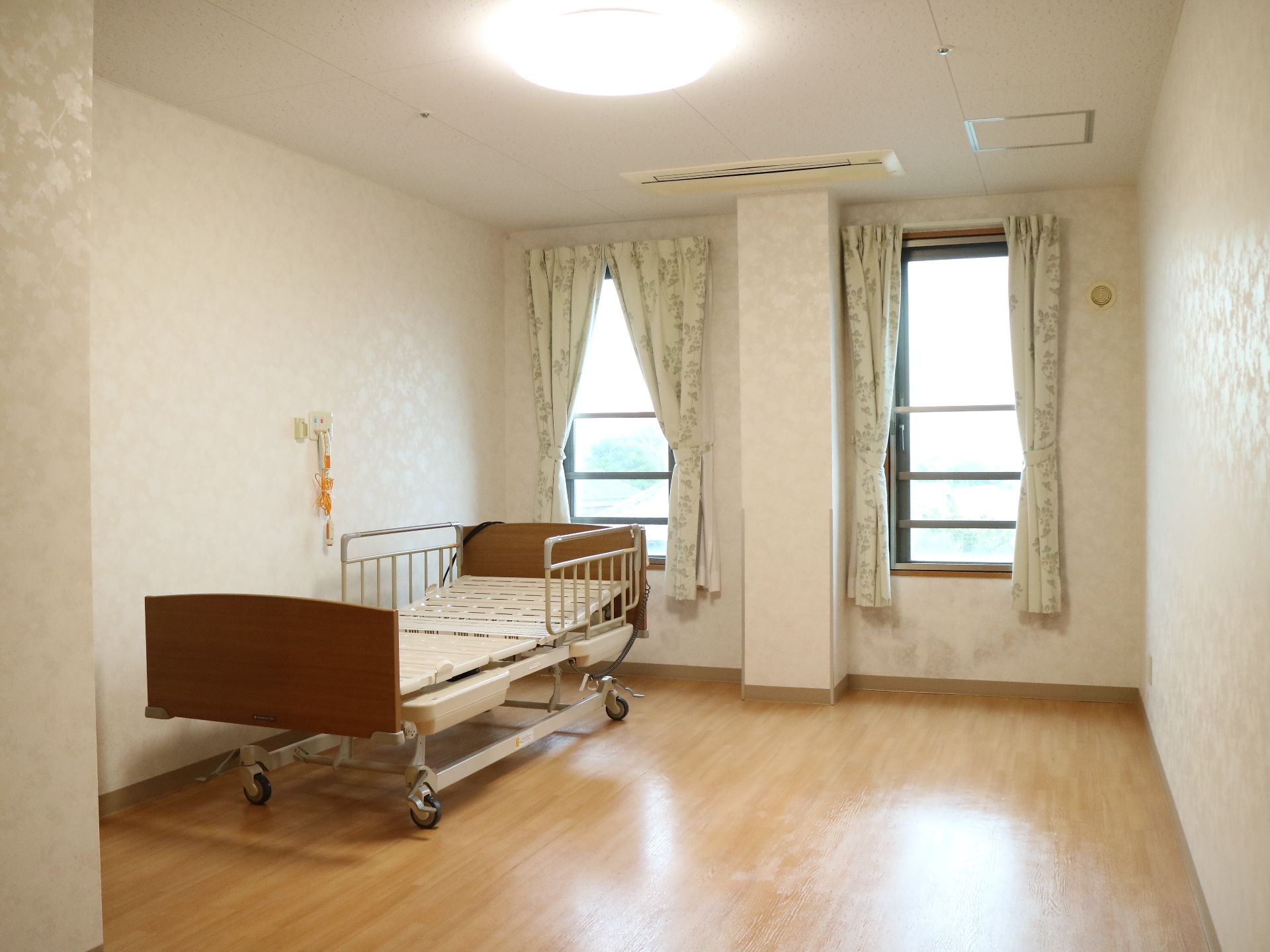 壁と同系色の花柄模様があしらわれている、明るく上品な雰囲気の居室