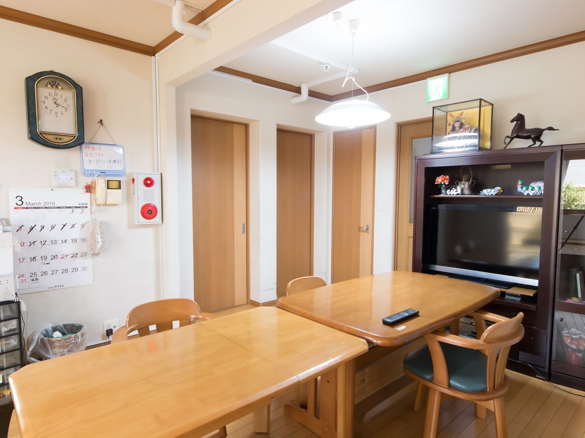 テーブルセットが配置されている。テレビが用意されており、テレビボードには小物が飾られている。壁には火災報知器が設置されている。