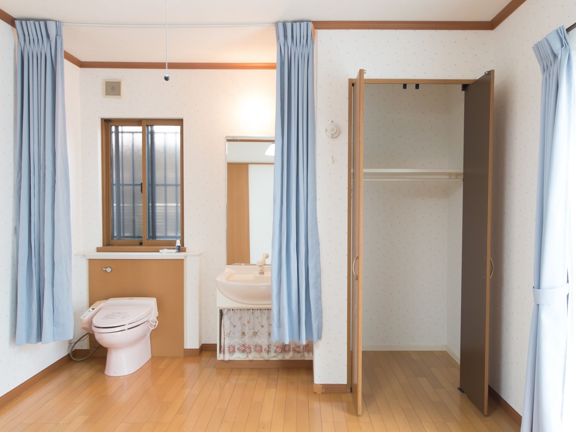 ワンルームの部屋に洗面台、トイレ、クローゼットが用意されており、コンパクトにまとまっている。間仕切りのカーテンがかかっている。