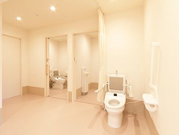 手すりと背もたれが付いたトイレが3つ用意されていて、ドアで開け閉めするタイプとカーテンで開け閉めするタイプがある。