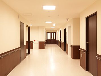 手すりが付いた広い廊下は白とダークブラウンの壁で落ち着いた雰囲気。エレベーターや防災設備もある。