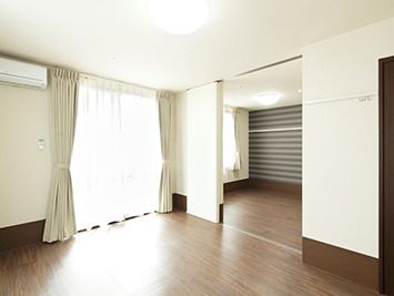 リビングと寝室スペースがそれぞれ就いたフローリングの部屋には大きな窓が付いていて、カーテンも設置されている。