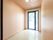 明るい色の木目の模様の壁や天井の部屋に、大きな窓が１つあり、日差しが屋内を照らしている。外には物干し台が置かれているのが見える。