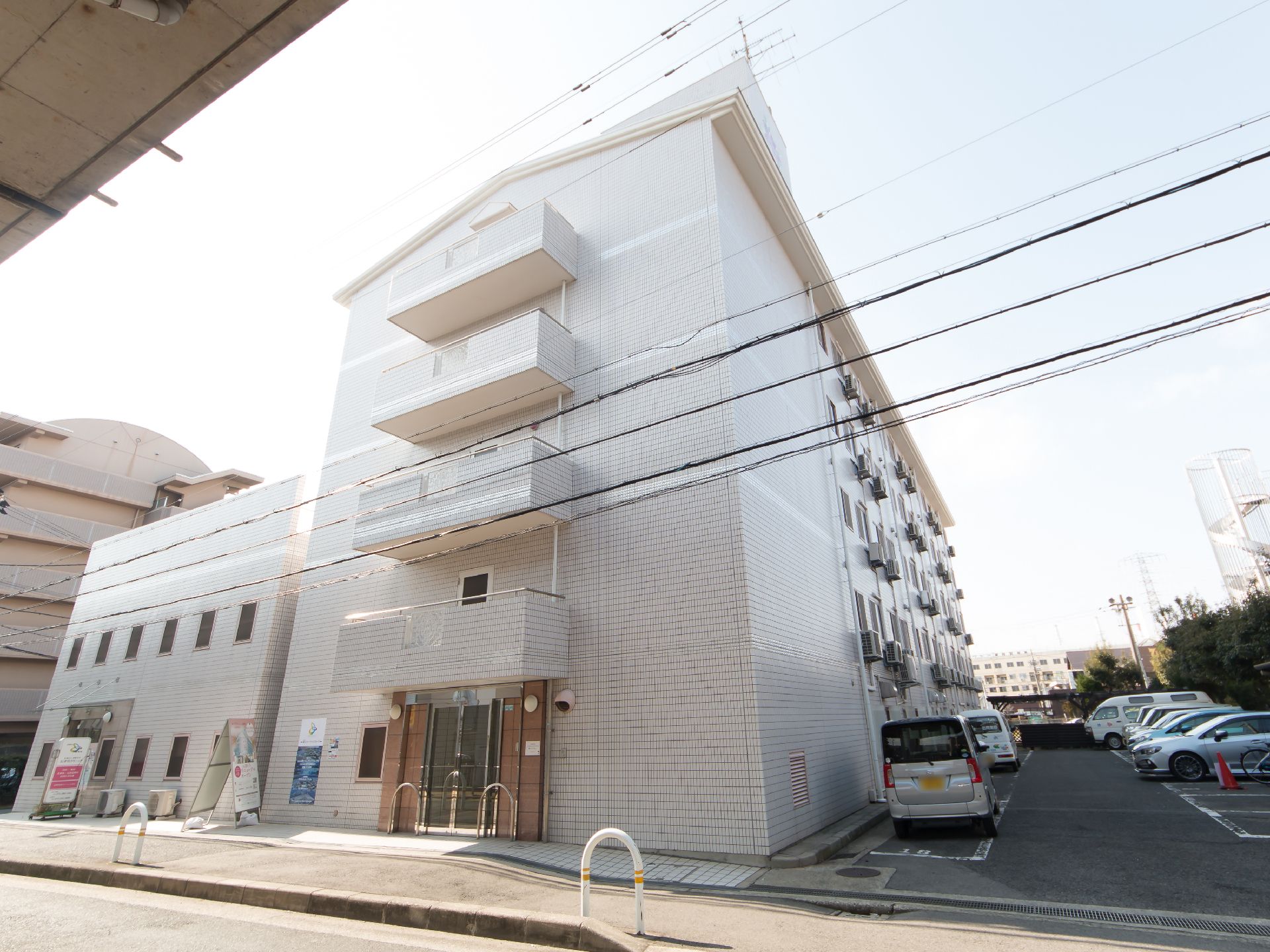 白色を基調とした外観の５階建ての施設である。施設右側の敷地内には多くの駐車スペースが確保されている。
