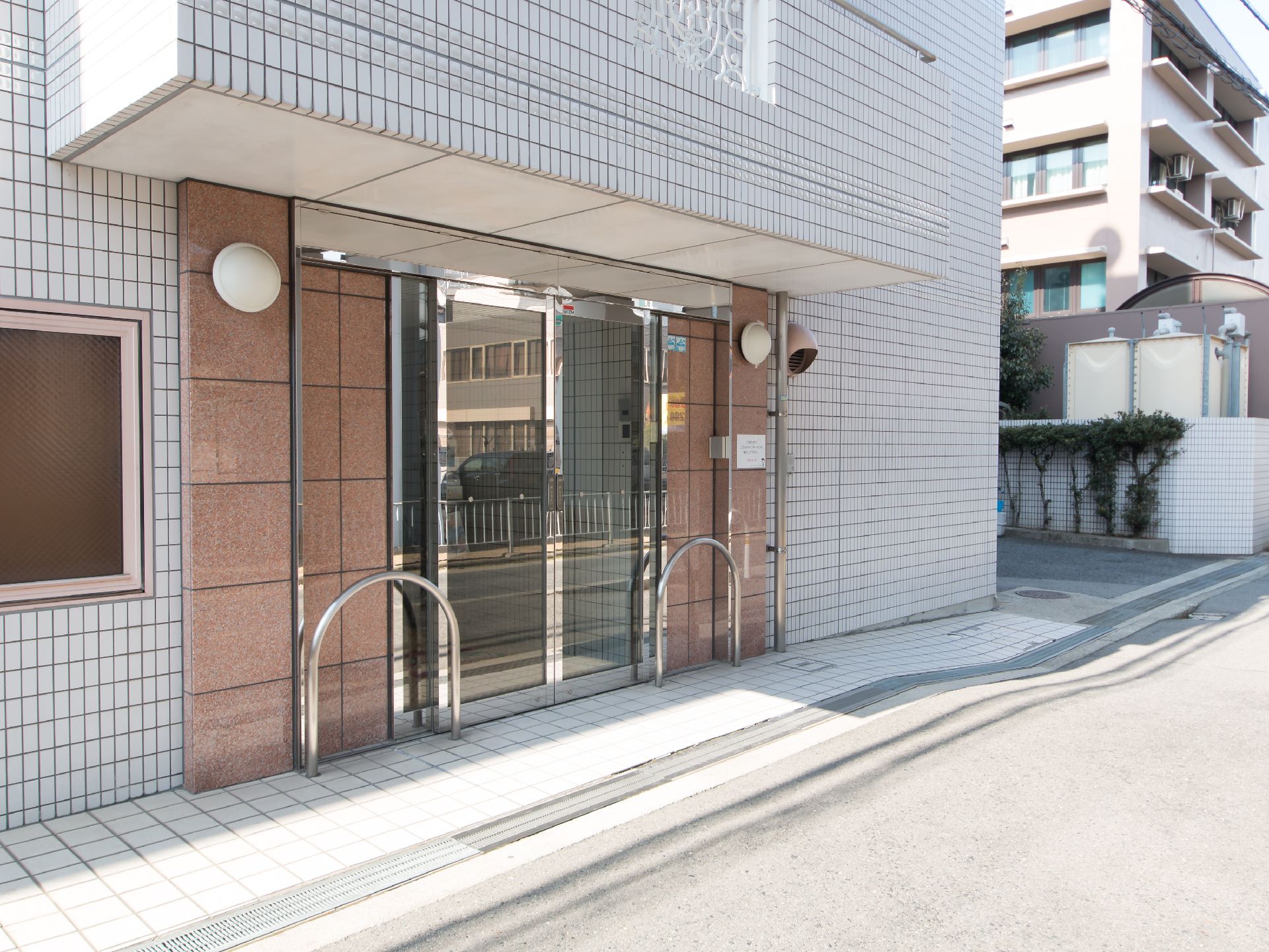 明るいグレー調のタイルとおしゃれなバルコニーが特徴的な、5階建て施設の外観
