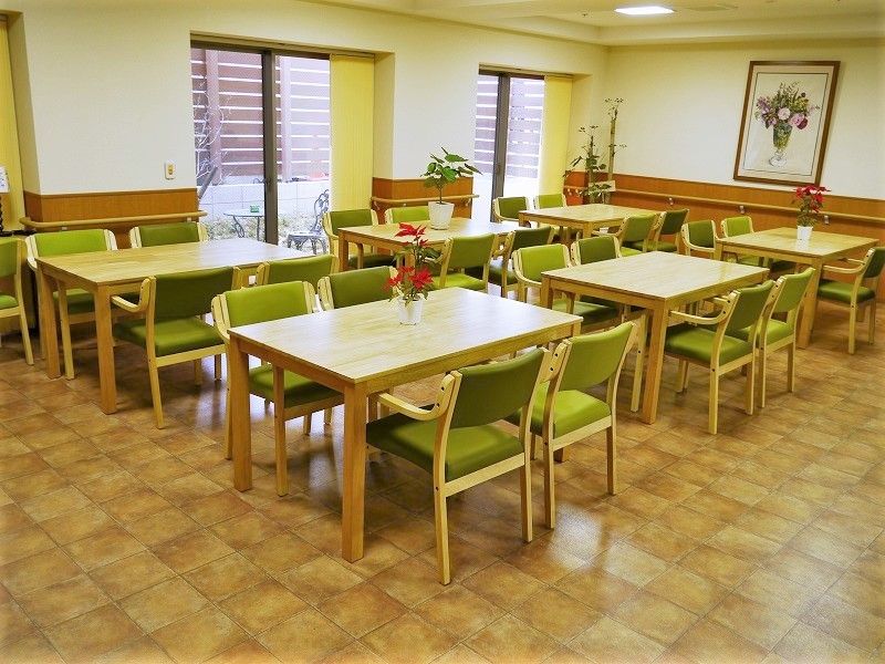 食堂には4人掛けのダイニングテーブルが並べられ、テーブルの上には観葉植物や花が飾られている。