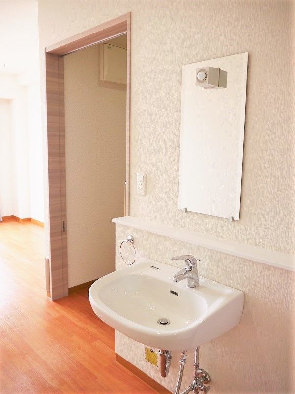 洗面所がシンプルで小さな造りだが、鏡やタオル掛けが付き、ひねらず水が出るなど細かな配慮がある。