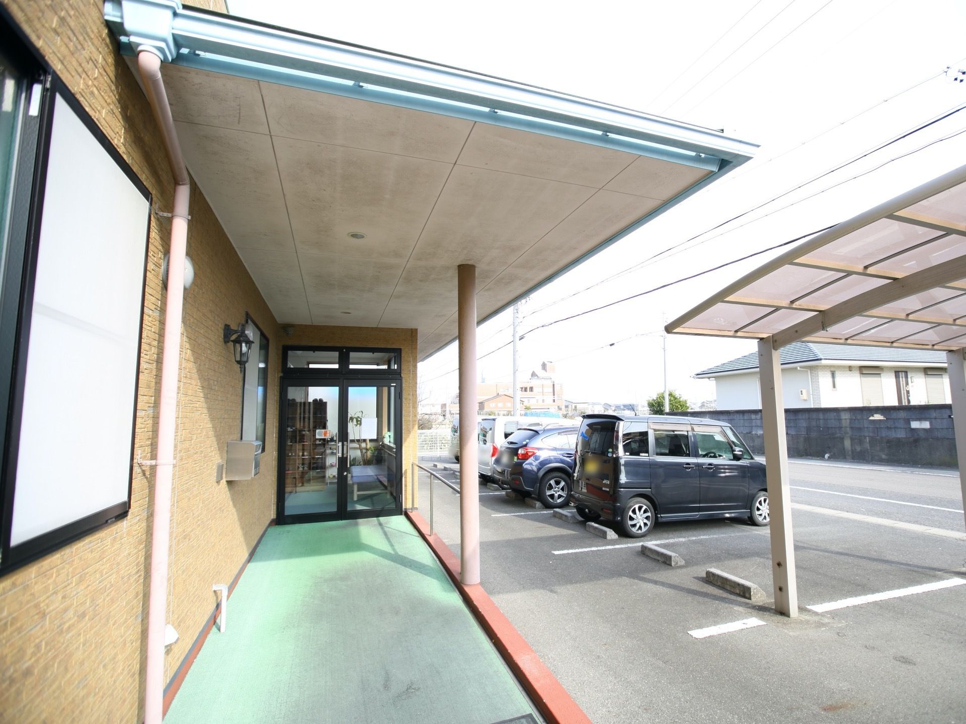 グリーンのスロープが設置され、片側に手すりががある。上部には広々とした、屋根を完備。すぐそばに駐車場がある。