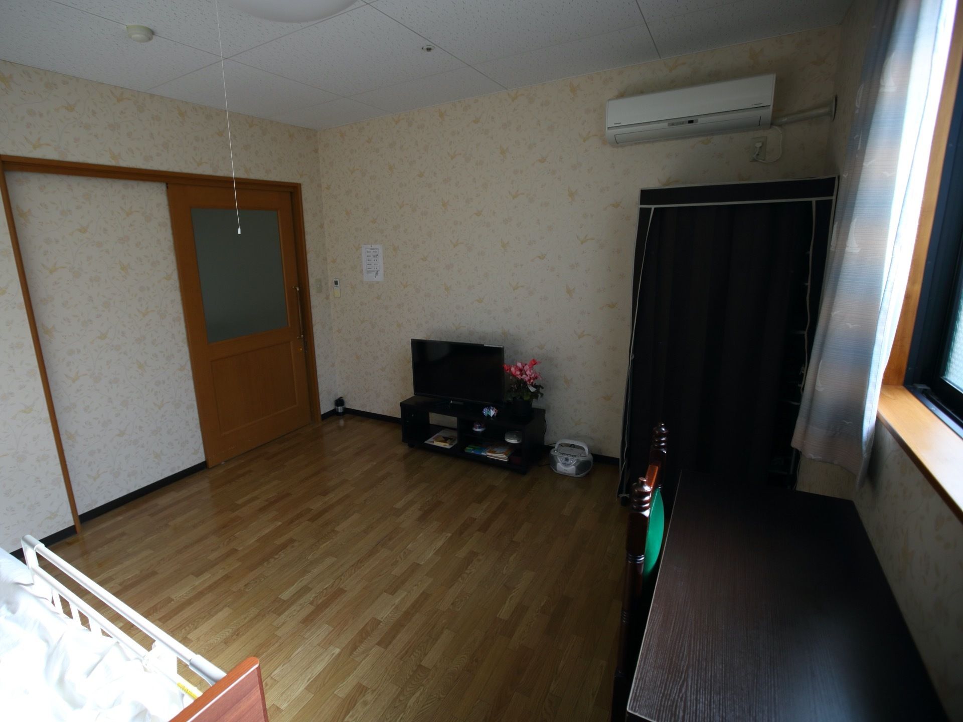 エアコンのある、フローリング部屋。個室仕様となっている。窓側にはデスクとチェアが置かれてある。テレビも設置されている。