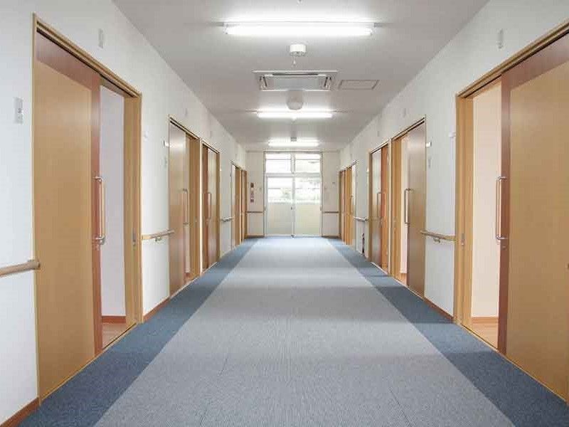 両サイドに居室があるまっすぐな廊下。手すりがあり、居室ドアは大きめで木製の引き戸を採用。