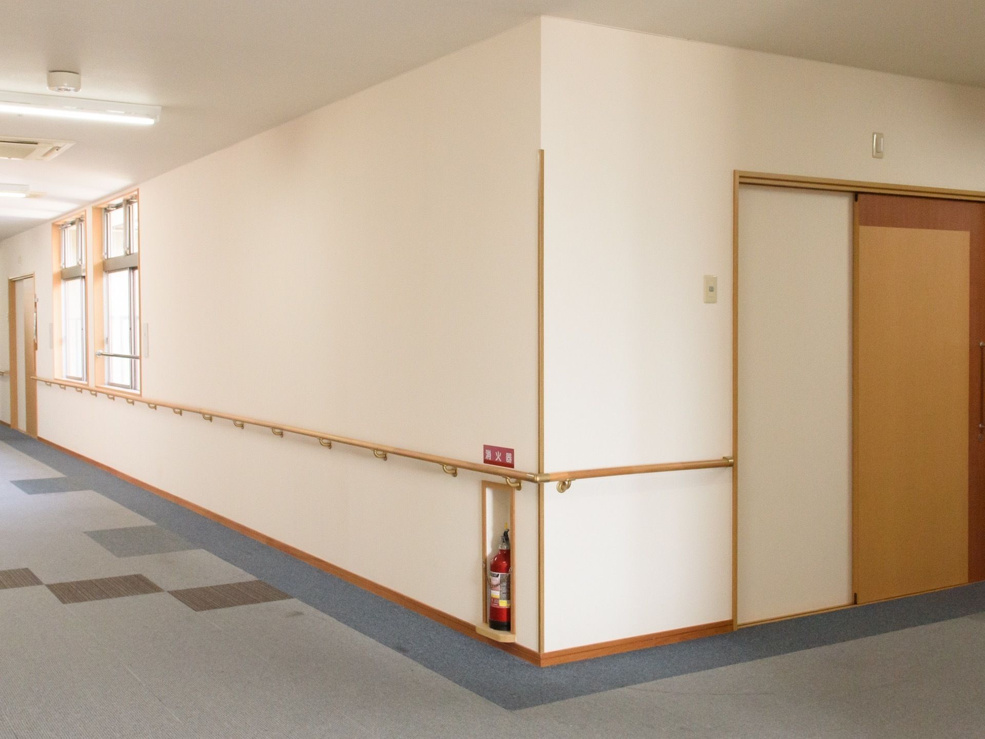 通路の壁のコーナー部分も途切れることのないよう、手すりを設置している。転倒した際のショックを和らげるように絨毯を敷き詰めている。