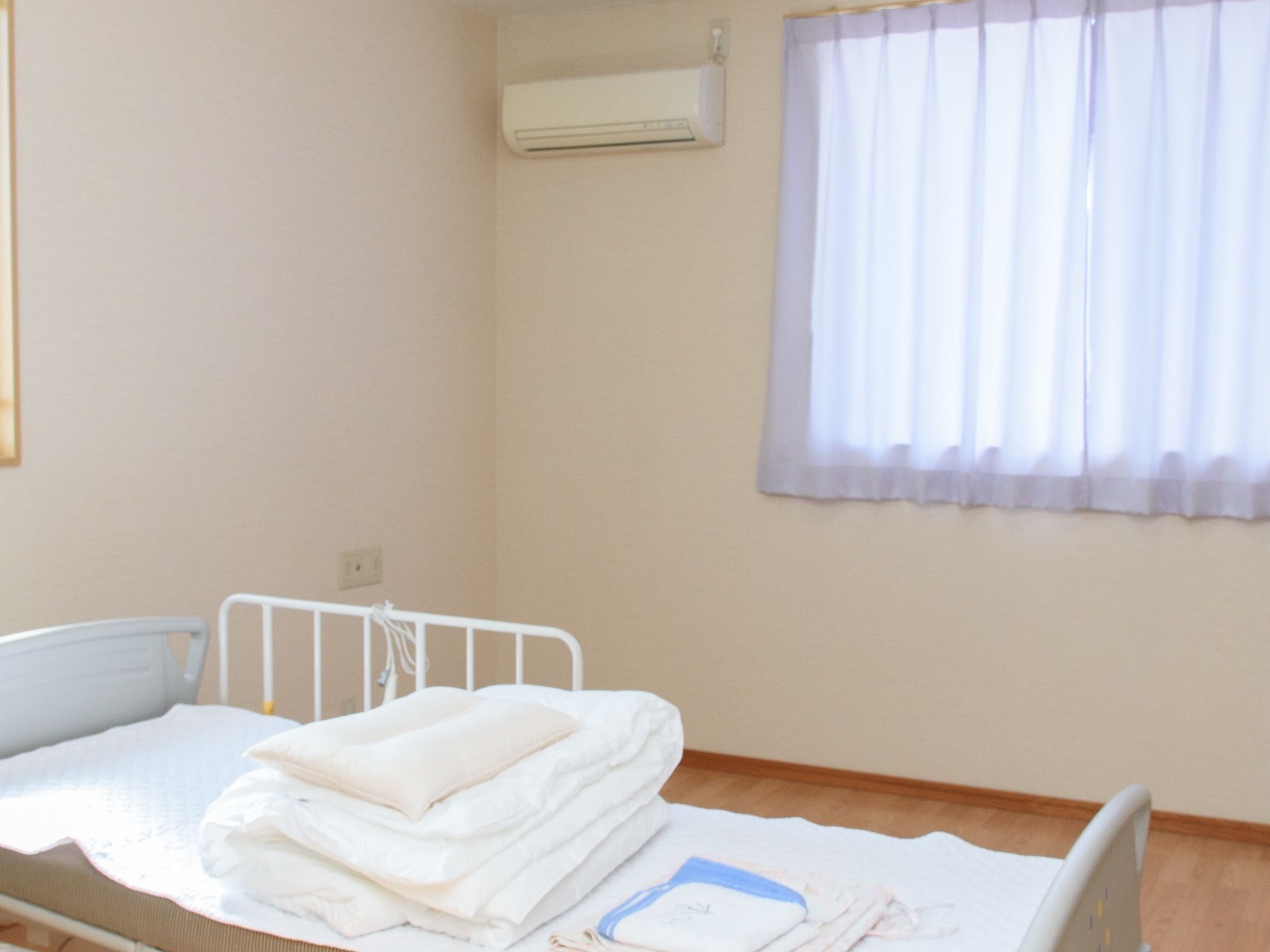 電動ベッド、腰高窓、空調設備が備わった居室である。フローリングの床は、掃除が行き届きやすく衛生的である。