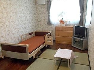 テレビやタンス、テーブル、介護ベッドなどが設置されたフローリングの部屋には畳も敷かれ、和の雰囲気。大きな窓が付き、明るい。