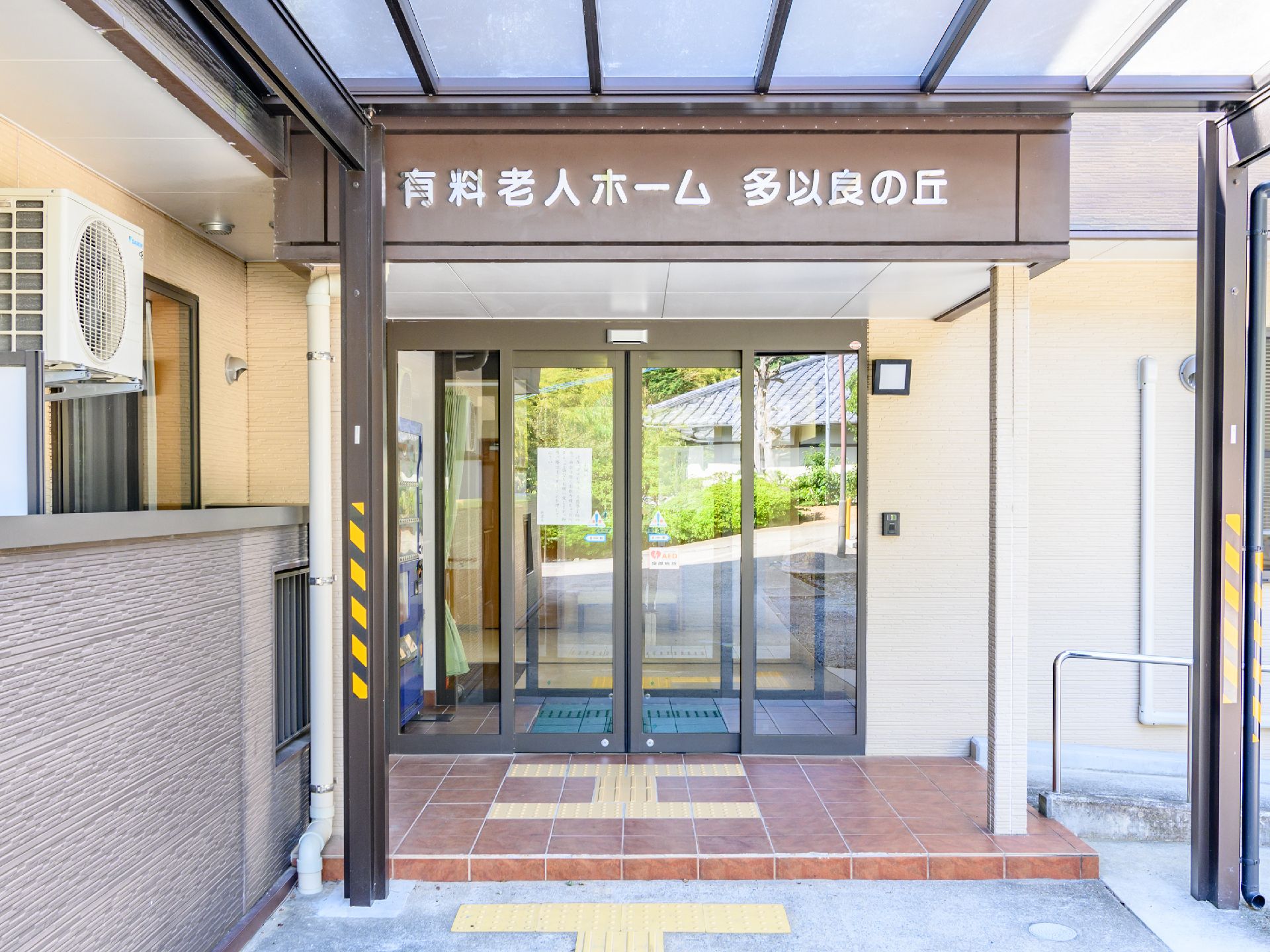 なにかを見て笑顔で手をたたいている高齢女性とスタッフの様子。施設での一場面の写真