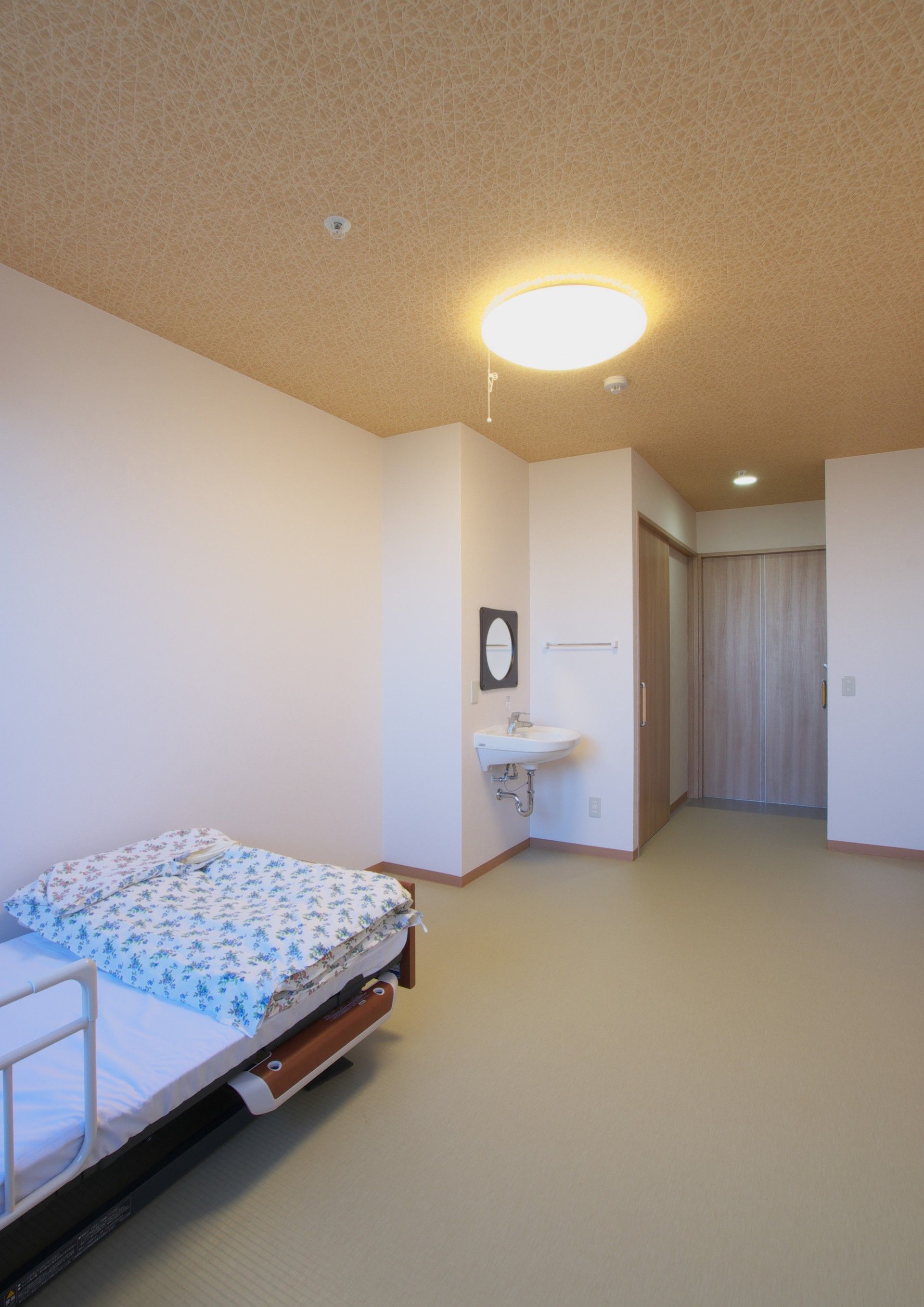 高齢者の方にタオルをかけてマッサージしているスタッフと振り返りながら会話する女性の様子