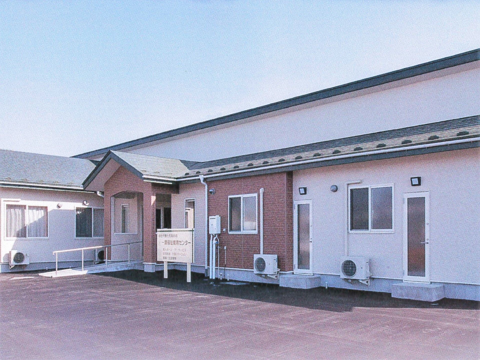 平屋建ての建物の前にはホームの看板があり、玄関にはスロープが付いている。