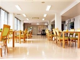 広々としたオールバリアフリーの施設内のリビングの様子。木製の家具類が写っている写真