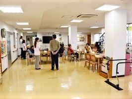 スタッフが施設の高齢者を見守る様子。施設内のリビングスペースの写真