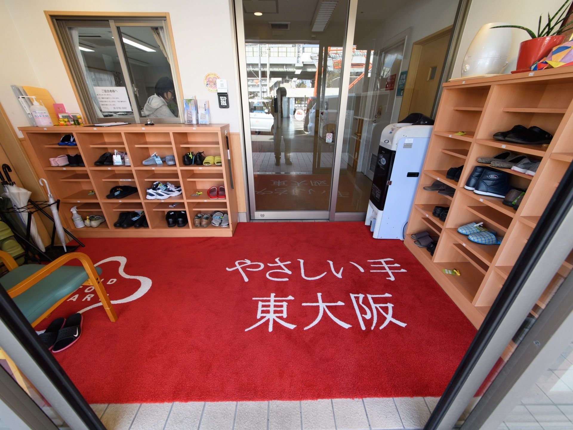 施設名がプリントされた真っ赤な絨毯が敷かれた玄関はバリアフリーとなっている。二重扉で、室内の温度を保っている。