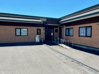 黄色いカーディガンを着た車いすの高齢女性が指さす方向をエプロンを付けた女性スタッフが一緒に見ている。