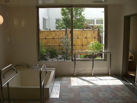 庭を眺めることができる大浴場には大きな浴槽があり、手すりが全域について安全に入浴できるようになっている。