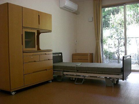 ベッドや大型の収納家具、チェストにエアコンなどがそろった居室。