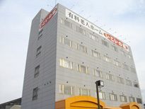 大きな文字でホーム名が書かれているグレーの大きな建物。周囲には大きな建物はない。
