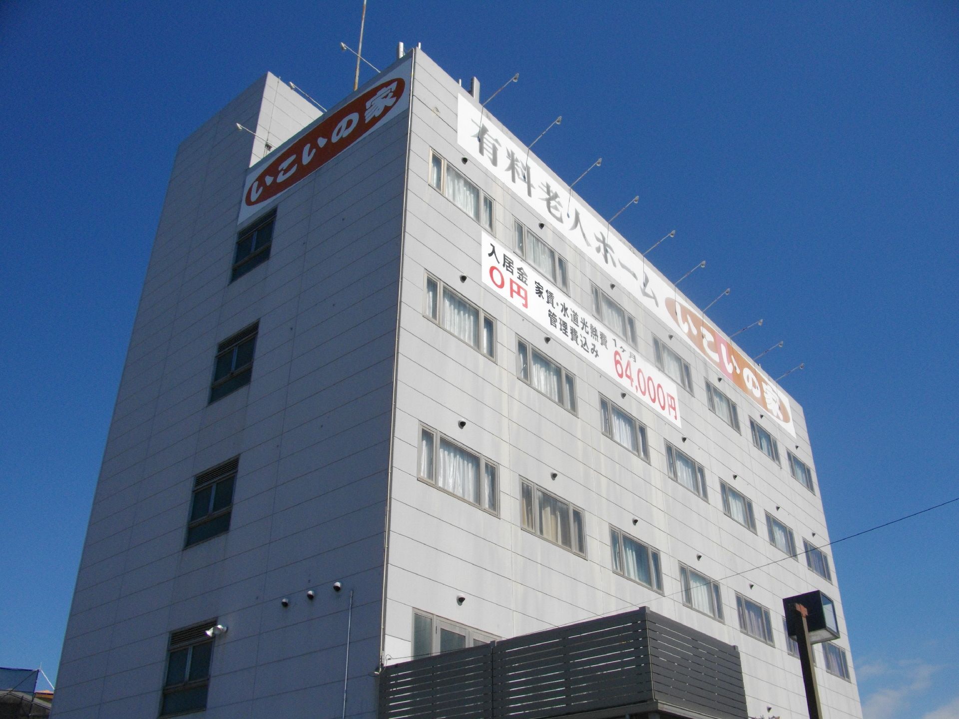 グレーの5階建ての建物の一番上には大きな文字でホーム名が書かれ、窓もたくさんついている。