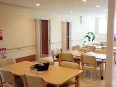 立てに長い空間にテーブルと椅子が複数組み並んでいる様子。施設内のリビングスペース