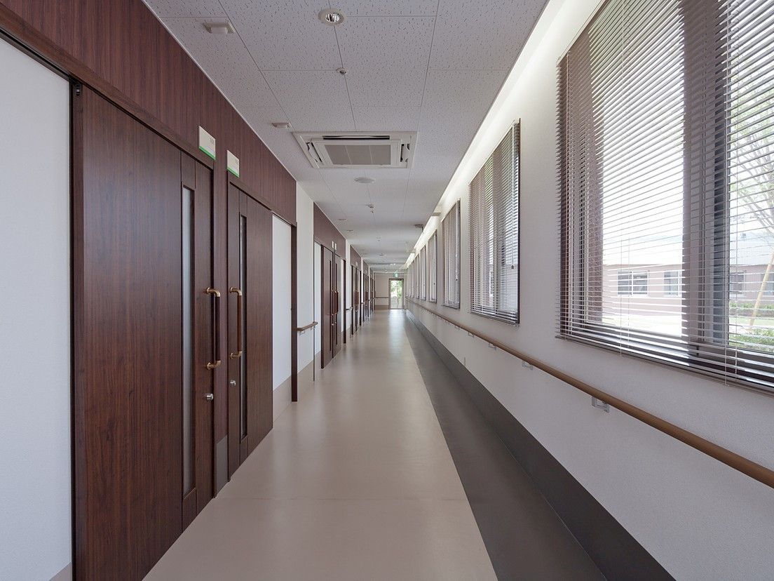 手すりが取り付けてある廊下の写真。片側が窓、反対側に個室が並んでいる