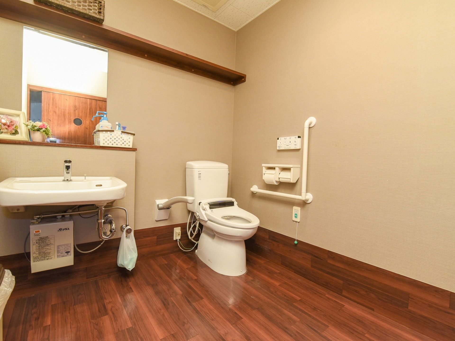 洗面台が備えつけられている個室トイレで、温水洗浄機能付きになっている。壁にはＬ字型の手すりや呼び出しボタンが設置されている。