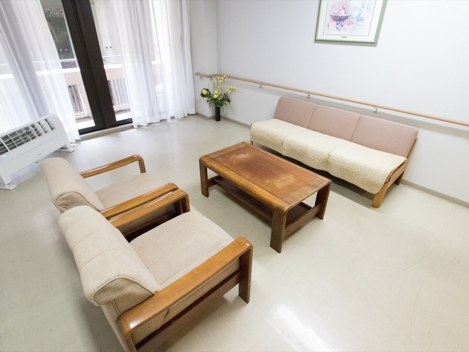 三人掛けのソファと一人掛けのソファが向かい合うように置かれている。空気清浄機が用意されている。花瓶には花が飾られている。