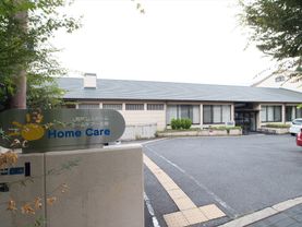 施設名が書かれた表札が門に設置されている。施設入り口近くは生垣が設けれられており、さまざまな植物が植えられている。