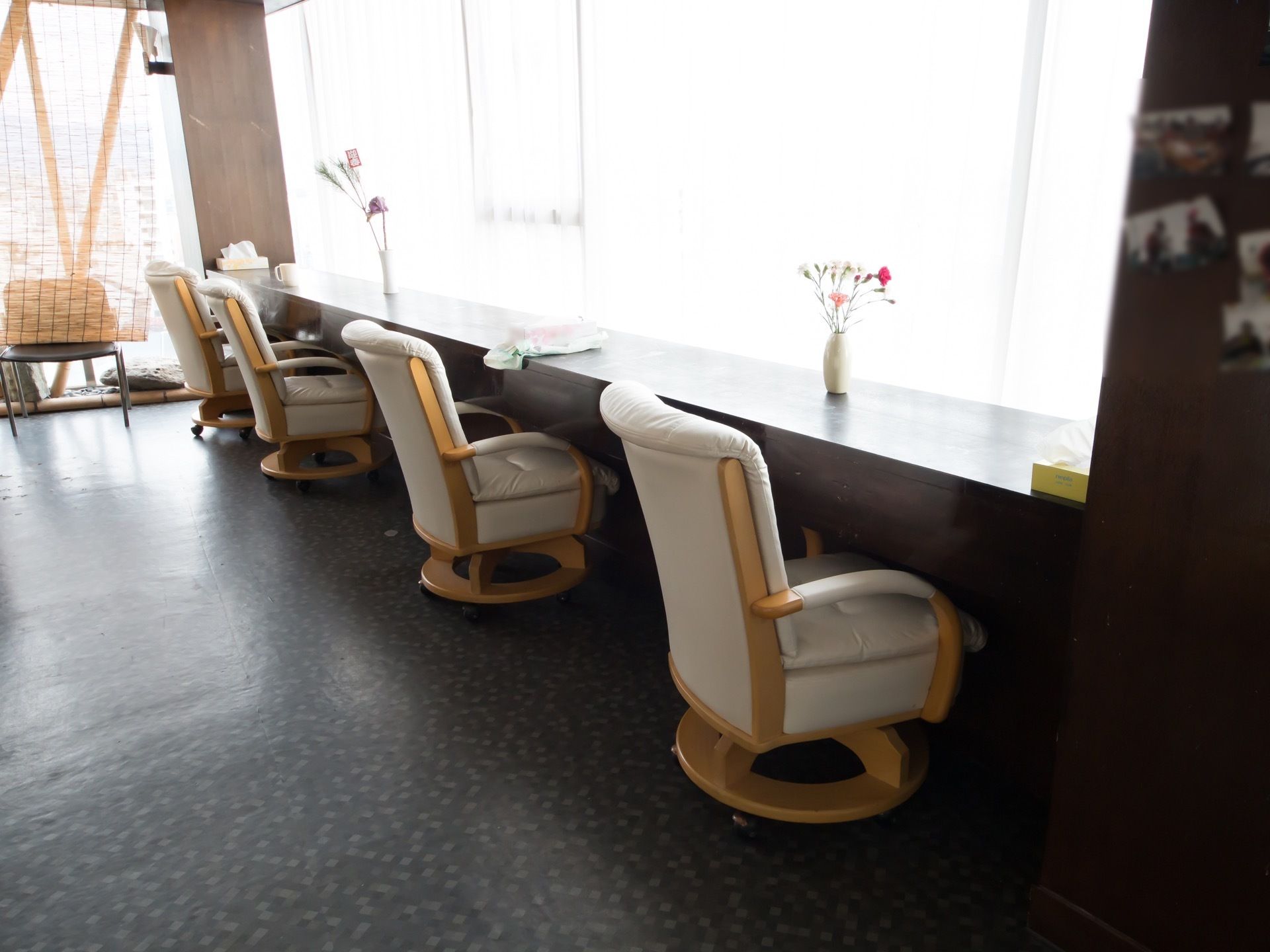 大きな窓がある休憩コーナー。窓に向かってソファチェアが４つ設置されている。左側にすだれがかかっている。