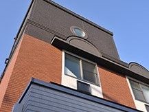 ツートンカラーの建物の外観写真。雨除け用のひさしがついたエントランス付近