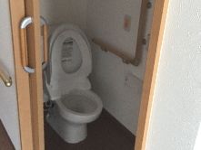 スライド式のドアが設置されたトイレにはエル字型の手すりとオレンジの呼び出しボタンも付いている。