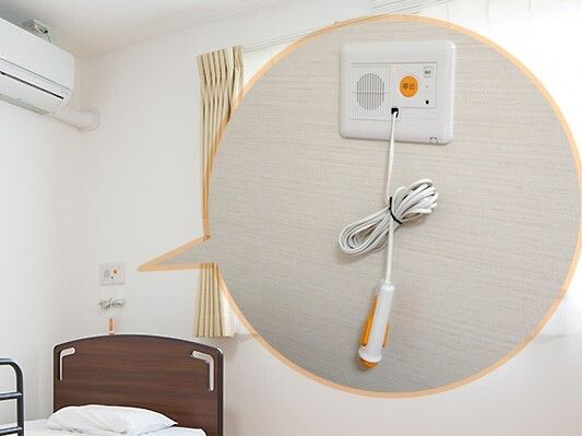 ベッドサイドには緊急通報装置があり、ベッドには寝具がセットされている。トイレには呼び出しボタンや手すりがある。