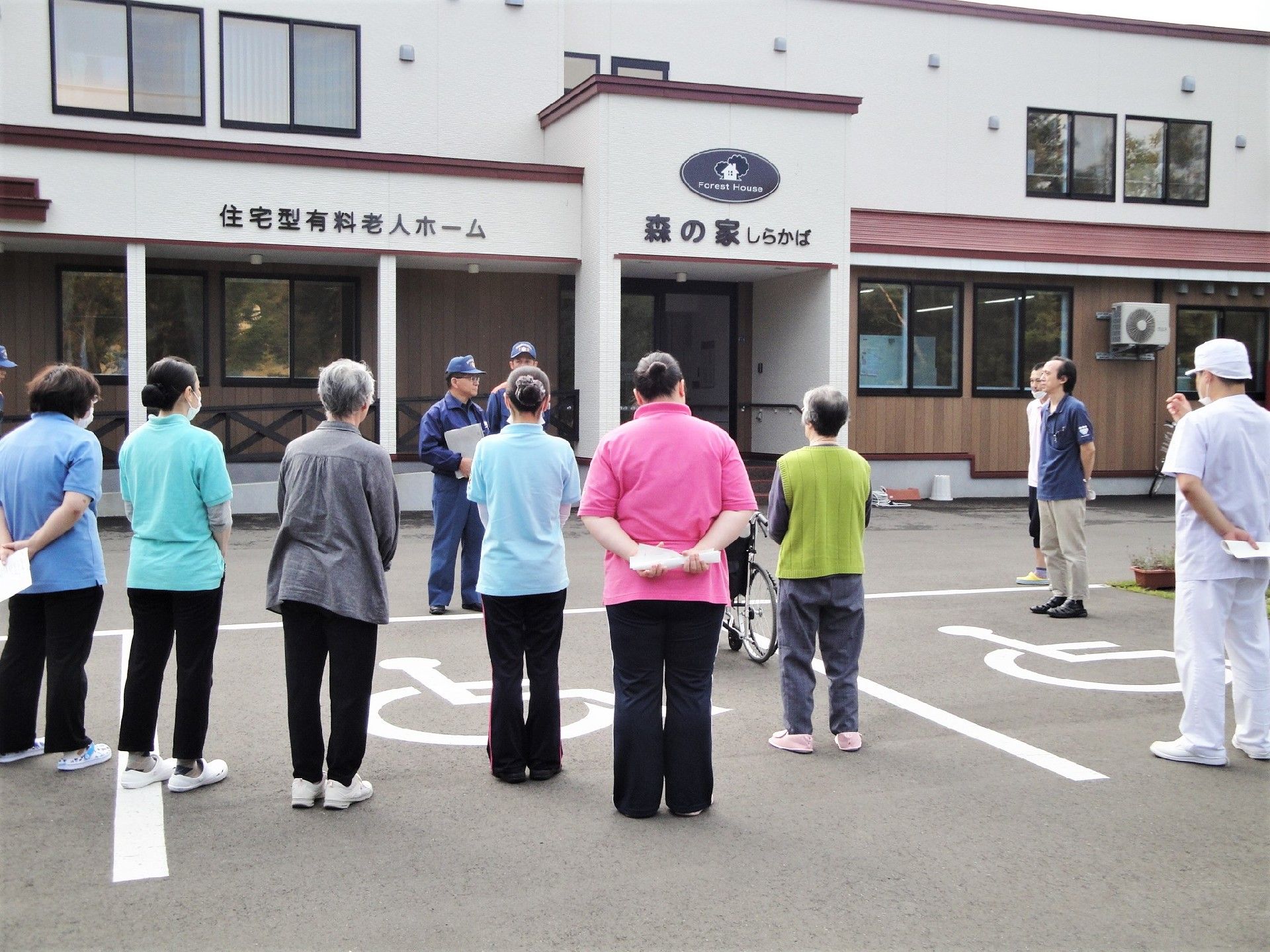 施設の前で消火訓練をしている様子。スタッフが並んでレクチャーを受けている